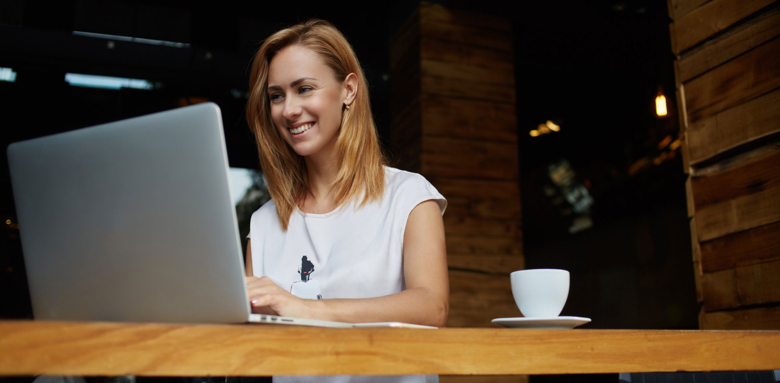 Young Woman Smiling While Working on Laptop